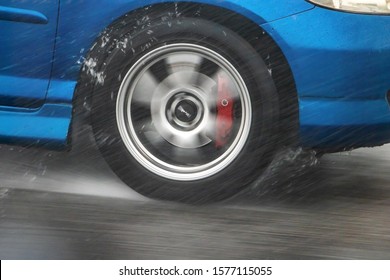 A Detail Of The Rear Wheel Of A Car Driving In The Rain On A Wet Road. Aquaplaning In Road Traffic.