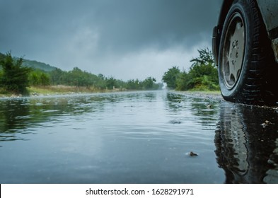 Detail of the rear wheel of a car driving in the rain on a wet road. Aquaplaning in road traffic.