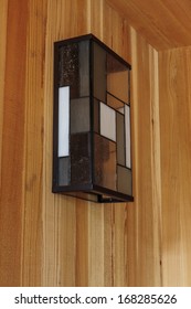 Detail Of Rectangular Modern Glass Light Fixture Of A Home's Front Porch. Light Fixture Is Off And Hangs Off A Wooden Wall. 