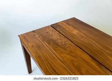 A detail of a rectangular wooden table in a white setting - Powered by Shutterstock