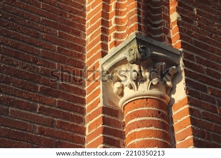 Detail of a red brick column with carved capital on top, on a medieval church in the south of France near Toulouse. Stock fotó © 