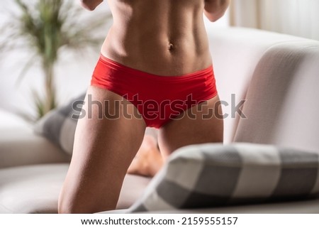 Detail of red menstruation panties on a body of a fit woman.