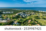 Detail rich aerial view of the Rio Mar Resort golf course in Rio Grande, Puerto Rico, showcasing its lush fairways, residential villas, and the vast coastline with the Atlantic Ocean in the distance.