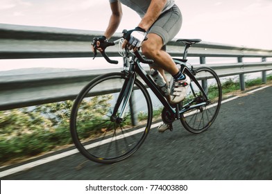 Detail Of A Road Bike With A Cyclist Pedaling On A Road.