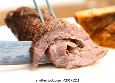 Detail of a roulade of baked meat being cut with knife.