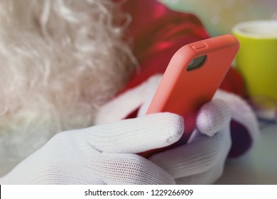 Detail Of Santa Claus (or Father Christmas) Hands Holding Cell Phone And Checking Social Media