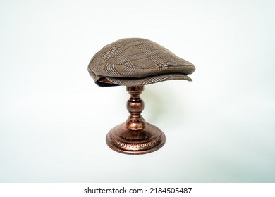 Detail Of Scally Or Flat Cap In Dark Brown Pattern  Herringbone Tweed Fabric Set On A Bronze Head Mannequin On A White Background