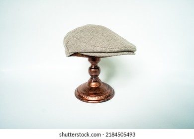 Detail Of Scally Or Flat Cap In Dark Brown Pattern  Herringbone Tweed Fabric Set On A Bronze Head Mannequin On A White Background