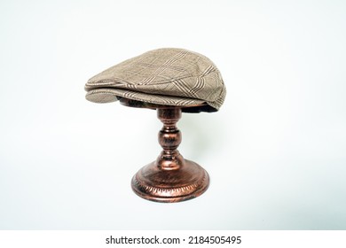 Detail Of Scally Or Flat Cap In Dark Brown Pattern  Herringbone Tweed Fabric Set On A Bronze Head Mannequin On A White Background