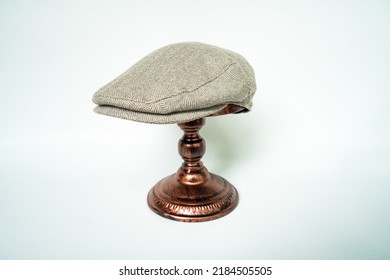 Detail Of Scally Or Flat Cap In Dark Brown Pattern  Herringbone Tweed Fabric Set On A Bronze Head Mannequin On A White Background