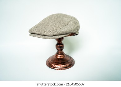 Detail Of Scally Or Flat Cap In Dark Brown Pattern  Herringbone Tweed Fabric Set On A Bronze Head Mannequin On A White Background