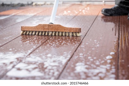 Detail of a scrubbing brush during spring cleaning on a wooden terrace with soap and splashes of water - Powered by Shutterstock