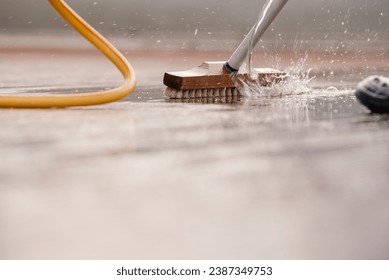 Detail of a scrubbing brush during spring cleaning of a wooden terrace floor with sparkling water with space for text - Powered by Shutterstock