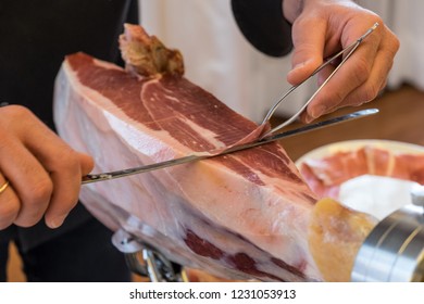 Detail with selective focus of some hands slicing Iberian ham slices