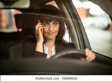 Detail Of Senior Business Woman Calling Mobile Phone While Driving Car At Night - View Through Front Window