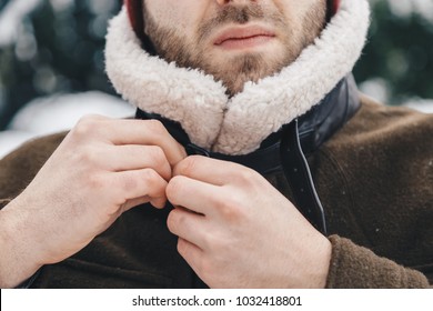 Detail shot of a man buttoning up his winter coat