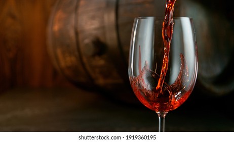 Detail Shot Of Pouring Red Wine From Bottle With Old Barrel Wooden Background