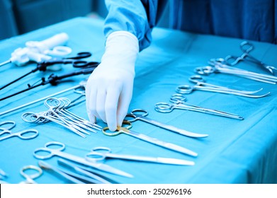 Detail shot of steralized surgery instruments with a hand grabbing a tool take with blue filter