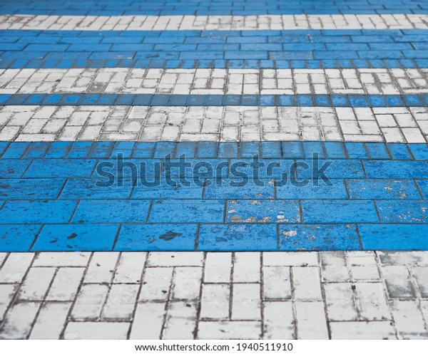 detail of a side view of a blue and white\
crosswalk on a cobblestone\
roadway