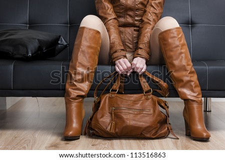 detail of sitting woman in brown clothes holding a handbag