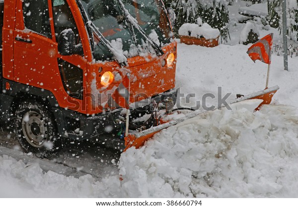 Detail of snow plow truck and blade in action\
during a heavy snow\
storm