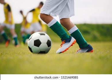 Detail soccer player kicking ball on field. Soccer players on training session. Detail soccer background. Close up of legs and feet of footballer on green grass