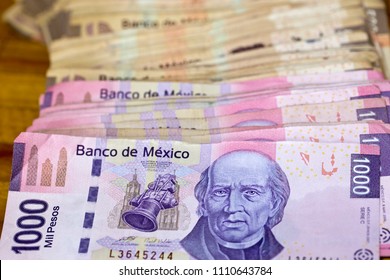 Detail of a stack of Mexican MXN banknotes with a denomination of 1000 pesos, showing obverse side of bill with image of Miguel Hidalgo y Costilla. One thousand Mexican peso notes, horizontal view.  