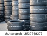 Detail of the stacks of smooth slick tires for endurance racing. A wall of many tires with blank references. New wheels with wear indicator