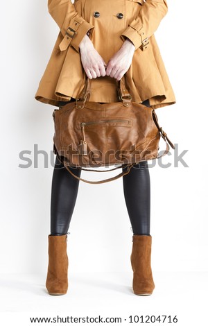 detail of standing woman wearing coat and fashionable brown shoes with a handbag