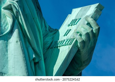 Detail of Statue of Liberty against blue sky, book with the date of USA's independence. New York City , United States.