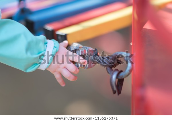 Detail of steel bolt anchor eye in\
metal. The end knot of steel rope. Mount colored suspension bridge\
in the Playground. Children\'s hand touches a metal\
nut