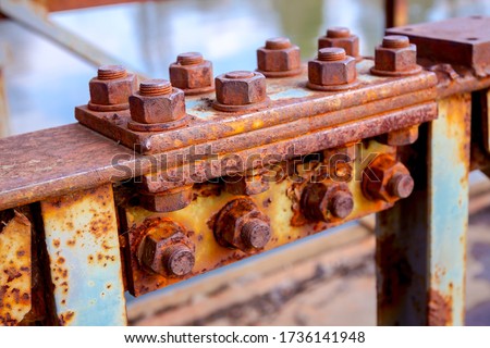 Detail of steel construction with old rusty screws on the fence of the bridge.