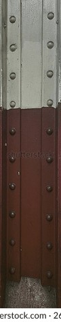 Detail of structural ironwork element.  Riveted steel pilar covered in white and brown thick coat of paint.