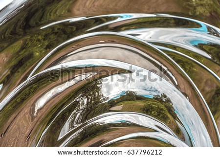Detail of the surface of metal sculpture. Beautiful abstract texture of the metal construction as background for design. Trees reflected in modern art object. Full frame. Curved distorted reflections.