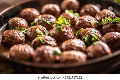 Detail of Swedish meatballs, kottbullar, in a pan topped with fresh parsley.