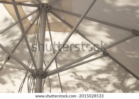 detail of table umbrella structure with shadows of trees reflected on it