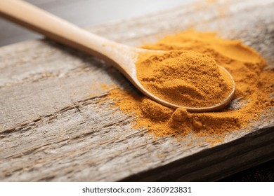 Detail of a teaspoon of ground turmeric on wooden surface - Powered by Shutterstock