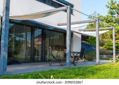 Detail of terrace of modern, white, cube, elegant, minimalist style passive house with large panoramic windows, grey shutters in maintained garden.