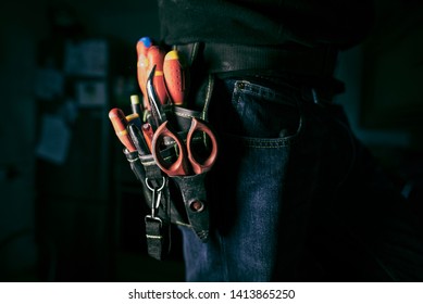 Detail of tools belt of electrician worker at home kitchen in low key screw, low key