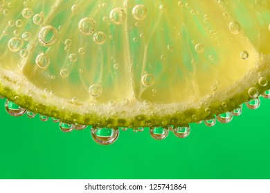 detail translucent slice of lime in a refreshing drink bubbles