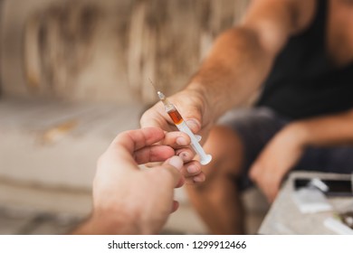 Detail Of Two Intravenous Drug User's Hands Sharing A Heroin Syringe; Junkies Shooting Up With Heroin