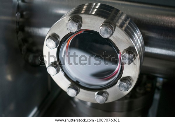 Detail of vacuum equipment with\
steel flanges bolted to the vessel in laboratory or industrial\
environment. Abstract industrial or technology\
background.