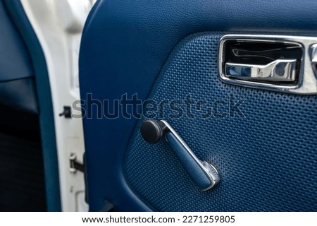 Detail view of a car door with a window crank handle