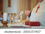 Detail view of a Catholic priest performing the sacrement of the Eucharist during Holy Communion in a Catholic church.