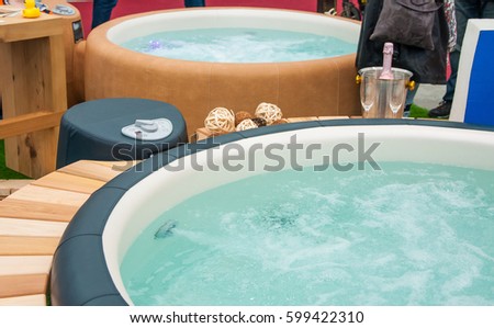 Detail view of luxury beautiful hot tub for relaxing, with decoration, towels, bottle of wine in nice interior.