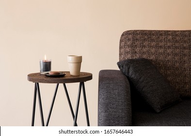 Detail view of modern round wood metal coffee table with cappuccino mug, glass candle burning by the side of sofa.  - Powered by Shutterstock