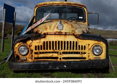 Detail view of a rusted, old, decommissioned vintage, yellow, pickup truck parked in a field of grass.  - Powered by Shutterstock