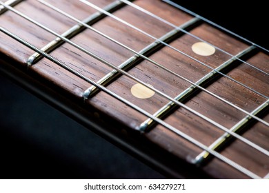 detail of vintage electric guitar fingerboard on dark background