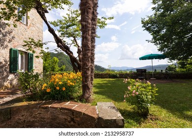 Detail of a wall of an ancient stone house with a flower garden aside. Nobody around. - Shutterstock ID 2132958737