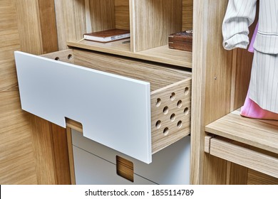 Detail of the wardrobe close-up. Modern wardrobe with opened wooden drawers. Wooden wardrobe with flat finger pull wardrobe doors. Oak veneered plywood cabinets with light gray painted cabinet doors